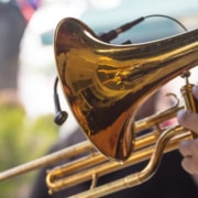 Close up image of a trombone being held by someone in an outdoot setting.