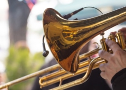 Close up image of a trombone being held by someone in an outdoot setting.