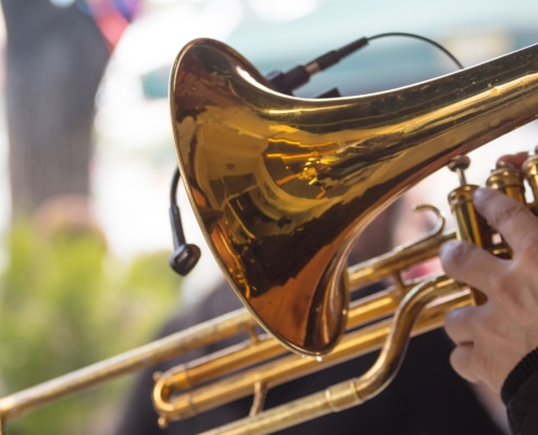 Close up image of a trombone being held by someone in an outdoot setting.