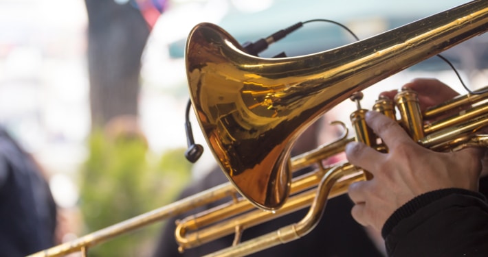 Close up image of a trombone being held by someone in an outdoot setting.