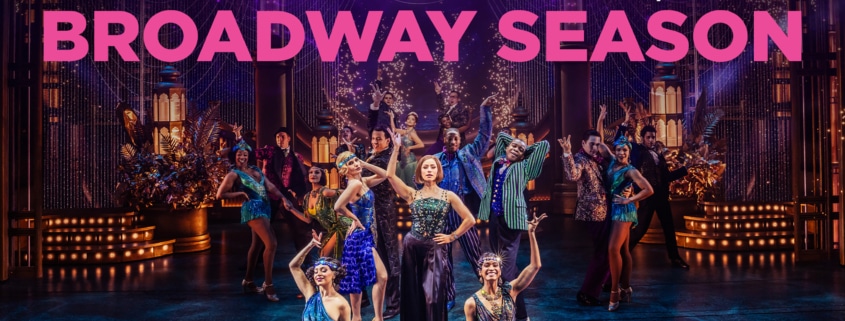 Colorful theatrical cast performing a lively dance number on a grand, art‑deco–inspired stage, with bold text above reading ‘Announcing the 2026/2027 Broadway Season.’ Bright costumes, dramatic lighting, and ornate set pieces create an energetic Broadway atmosphere.