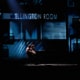 Theatrical stage performance with two performers at a piano in a dimly lit scene featuring a backdrop labeled ‘Ellington Room’.