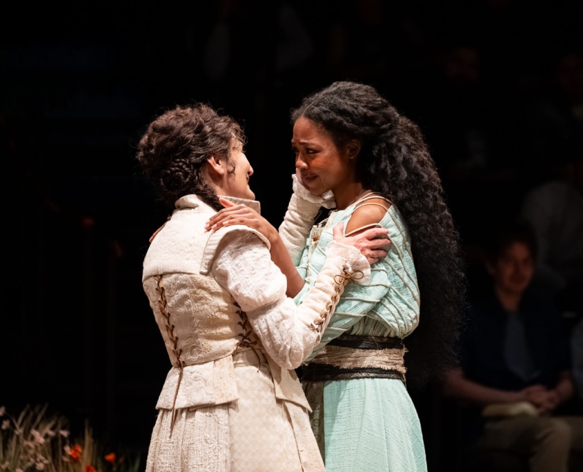 Two performers face each other closely and hold one another by the shoulders during an intimate moment onstage.