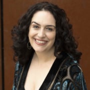 Person with curly hair wearing a patterned velvet-style shirt