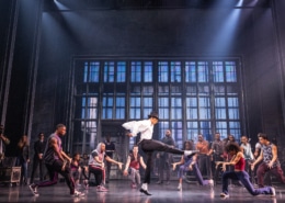Cast performing a high‑energy dance number in vibrant purple costumes on stage in the MJ musical touring production.