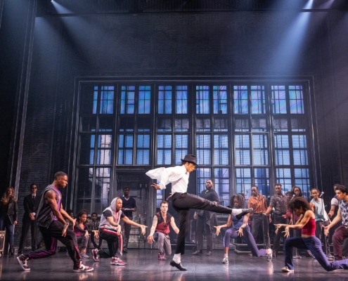 Cast performing a high‑energy dance number in vibrant purple costumes on stage in the MJ musical touring production.