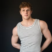 Person wearing a striped sleeveless shirt against a dark background”