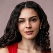 Person with long curly hair wearing a red top in a portrait setting