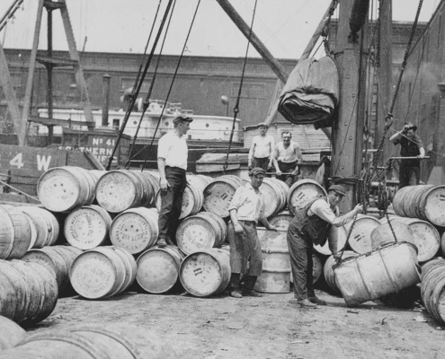 Early 20th‑century dock workers handling barrels during waterfront shipping operations