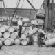 Early 20th‑century dock workers handling barrels during waterfront shipping operations