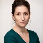 Headshot of a woman wearing a dark teal, v-neck tee shirt this her hair pulled back