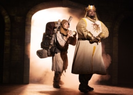 Medieval comedy scene from Monty Python’s Spamalot musical featuring knights and a traveler entering a castle