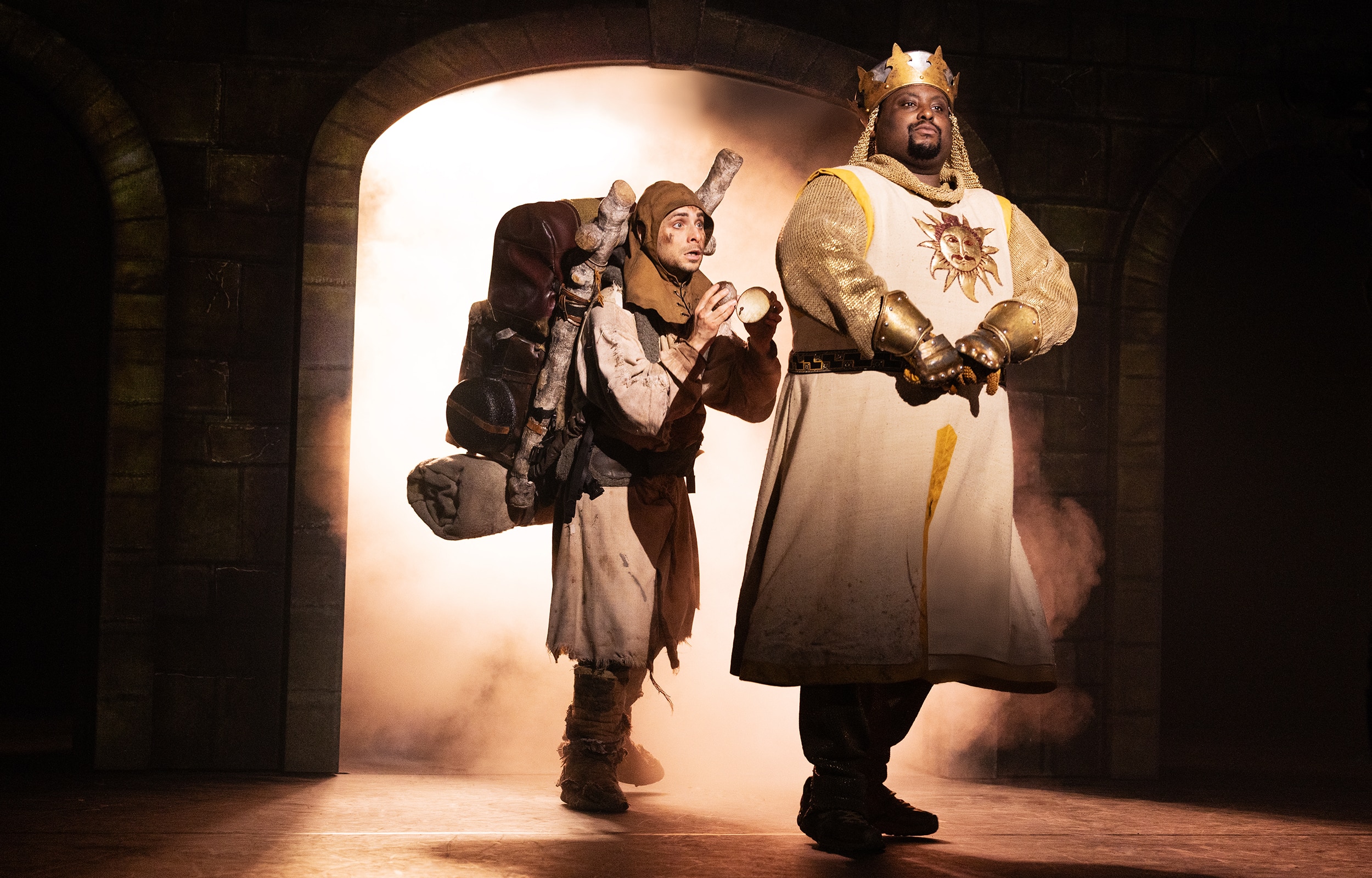 Medieval comedy scene from Monty Python’s Spamalot musical featuring knights and a traveler entering a castle