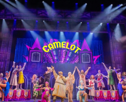 Full cast of Spamalot musical performing Camelot number on colorful stage with dancers and knights”