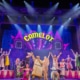 Full cast of Spamalot musical performing Camelot number on colorful stage with dancers and knights”