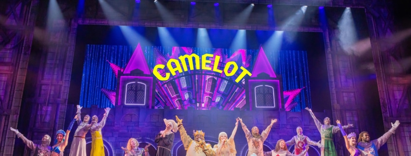 Full cast of Spamalot musical performing Camelot number on colorful stage with dancers and knights”