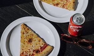 Large New York-style cheese pizza slices from Fuso Pizza & Pasta at Denver Milk Market served on white plates with a soft drink.