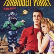 Movie poster for Forbidden Planet. A person in a bright red futuristic uniform stands in the foreground holding a ray gun while another person in a light-colored outfit stands beside them. Behind them, a large robot carries an unconscious figure across a rocky alien landscape. A ringed planet appears in the night sky above, with the film title displayed in bold yellow and red text.
